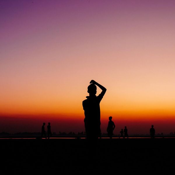 Silhouette of a man stretching against a bright, energetic background.